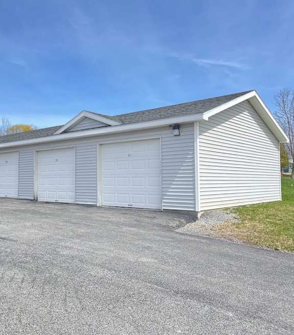 A carport with several cars parked in front of a two-story building.