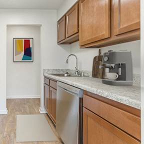A kitchen with a coffee maker on the counter and wooden cabinets