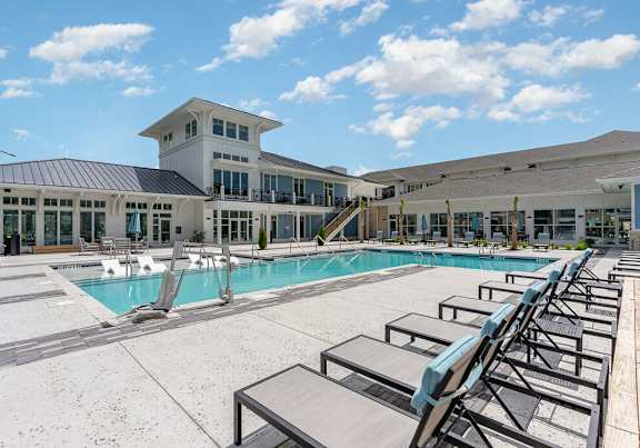 A large swimming pool with lounge chairs and a building in the background.