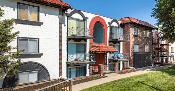 A white building with a red roof and a balcony with a blue curtain.