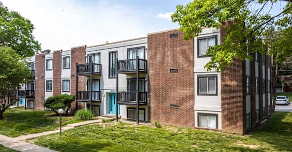 A row of red brick apartment buildings with green trees in front.