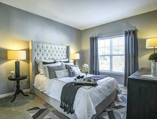 A well-lit bedroom with a large bed and a nightstand at Hillside Club Apartments, Livingston, NJ, 07039