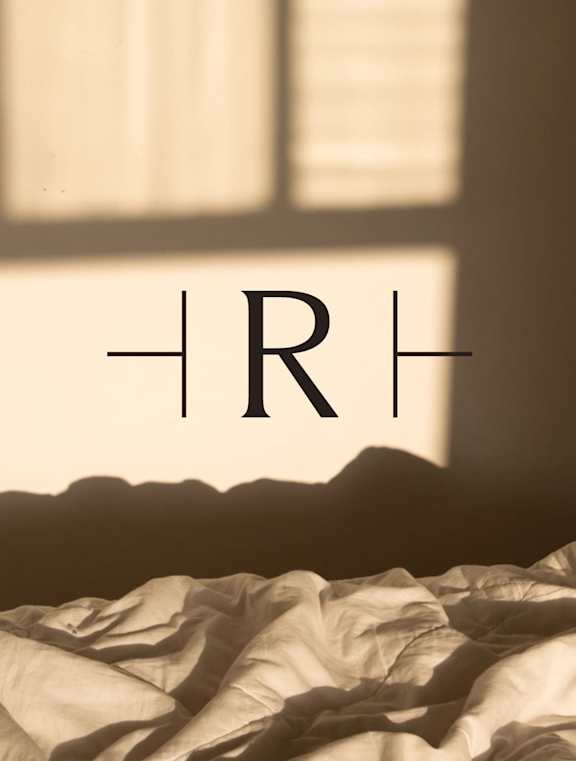 A bed with crumpled sheets and a window in the background.