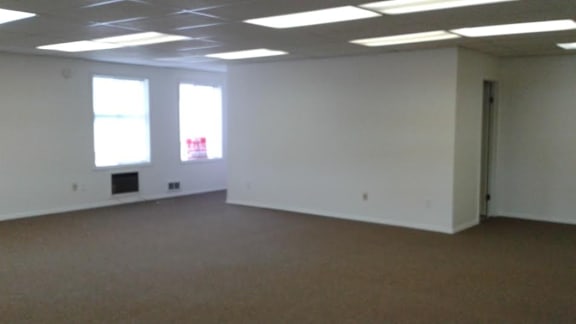an empty room with a door and three windows
