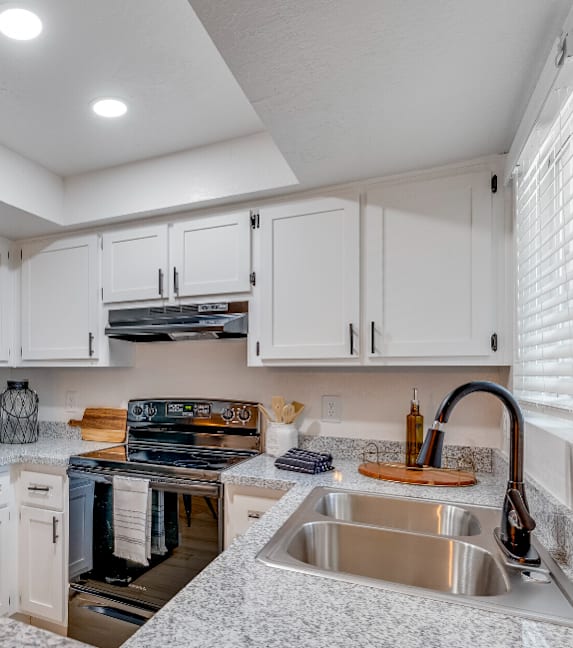 a kitchen with white cabinets and black appliances and a sink