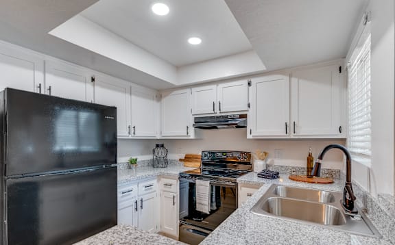 a kitchen with white cabinets and black appliances and a sink