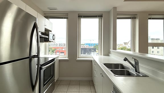 A modern kitchen with a stainless steel refrigerator and wooden flooring.