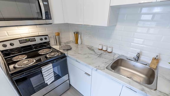 A modern kitchen with a stainless steel refrigerator and wooden flooring.