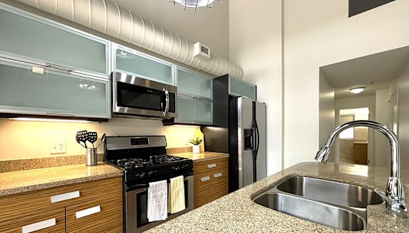 A modern kitchen with a stainless steel refrigerator and wooden flooring.