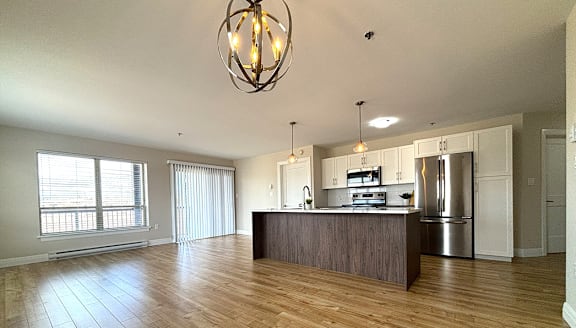 A modern kitchen with a stainless steel refrigerator and wooden flooring.