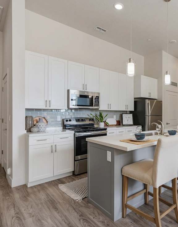 A kitchen with white cabinets and a wooden island.