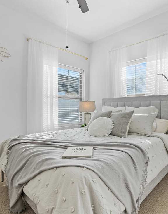 A bed with a grey comforter and pillows is in the image.