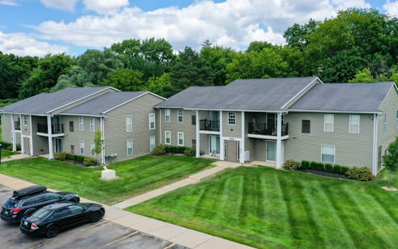 an aerial view of an apartment complex with cars parked in front of the lawn