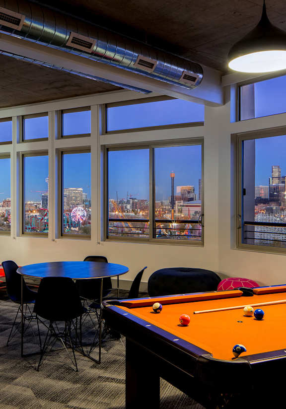 A room with a pool table and a table with chairs.