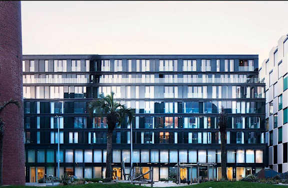 a glass building with palm trees in front of it
