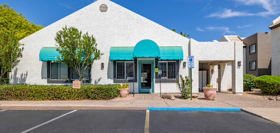 a white building with blue awnings and a blue parking lot