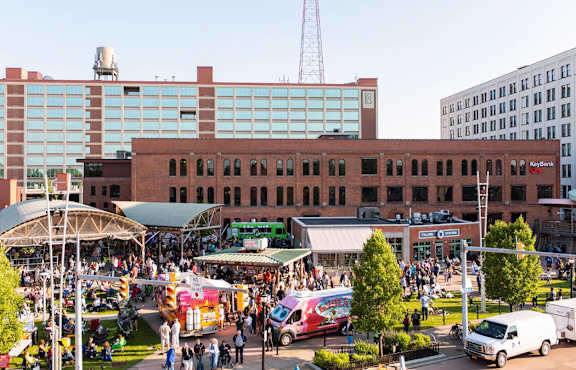 A busy outdoor market with a variety of food trucks and people walking around at The Lofts at Elk Terminal Apartments, Buffalo