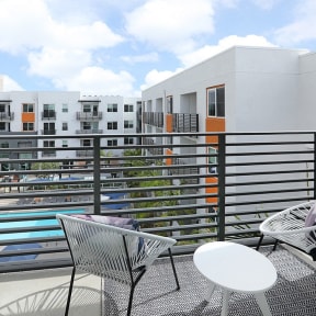 a balcony with a table and chairs and a building in the background