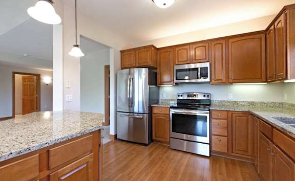 an empty kitchen with wooden cabinets and stainless steel appliances