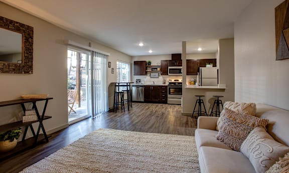 A modern living room with a white couch and a large mirror on the wall at Commons at Redwood Creek Apartments, Beaverton, 97008