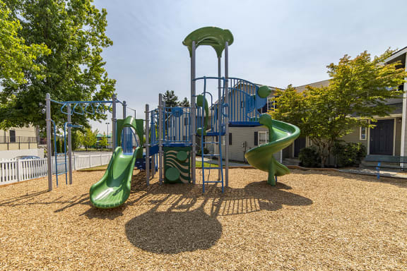 Playground surrounded by trees, landscaping and homes at Arterra Apartments, Kent