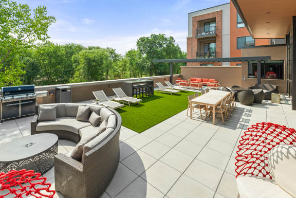 A roof-top terrace with a grilling station, fire pits, a comfortable seating area, chairs, tables, and lounge chairs on artificial turf. at Keva Flats, Exton, PA, 19341