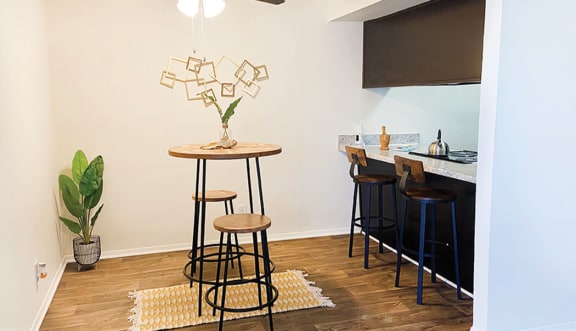 a dining room with a bar with stools and a ceiling fan