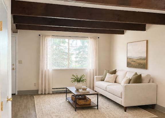 A living room with a couch, coffee table, and a painting on the wall.