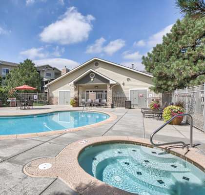 A hot tub sits in the middle of a pool surrounded by a patio and a building.