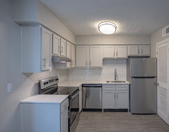an empty kitchen with white cabinets and stainless steel appliances