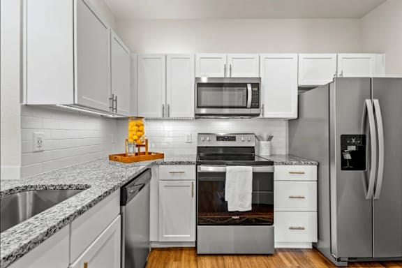 a kitchen with stainless steel appliances and white cabinets at Cypress Creek at River Oaks, TX 75165