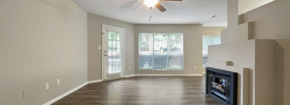 an empty living room with a ceiling fan and a fireplace