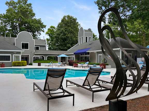 A poolside area with a large sculpture and lounge chairs.