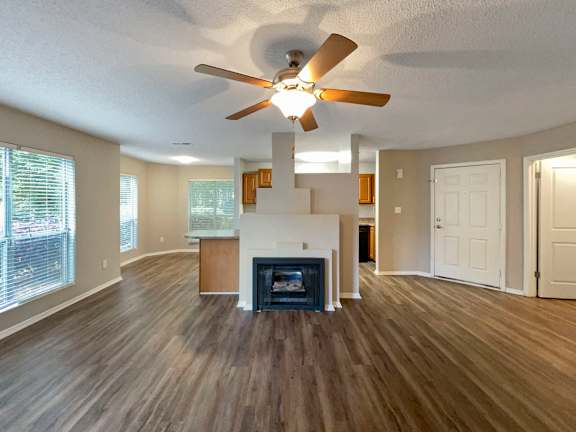 an empty living room with a ceiling fan and a fireplace