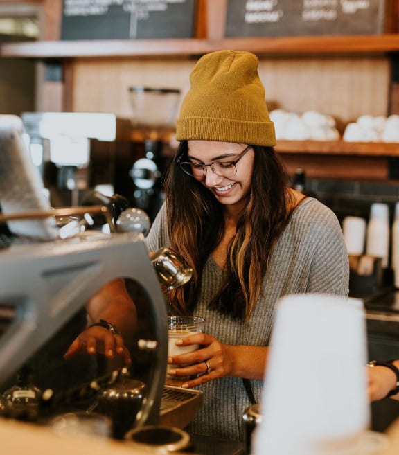 a woman drinking a glass of coffee at a coffee shop