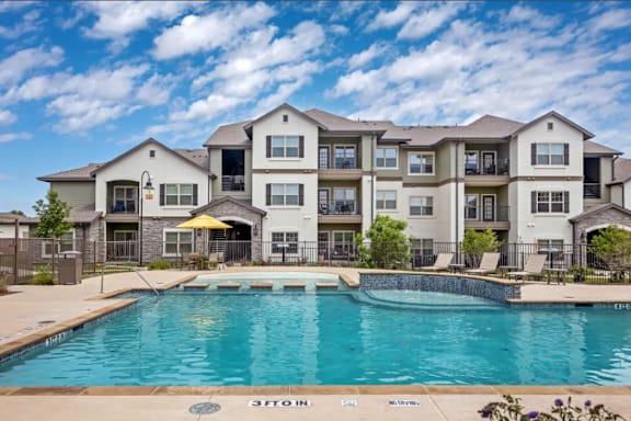 a swimming pool with an apartment building in the background at Cypress Creek at River Oaks, Waxahachie Texas