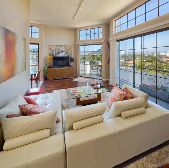 A living room with a couch, television and a view of a balcony.