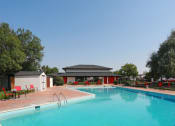 Thumbnail 6 of 18 - a swimming pool with red chairs around it and a white building in the background