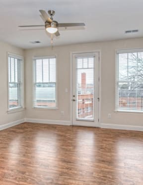 an empty living room with a ceiling fan and windows