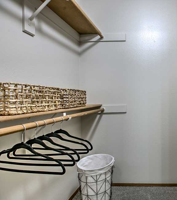 A white wall with a shelf and a trash can.