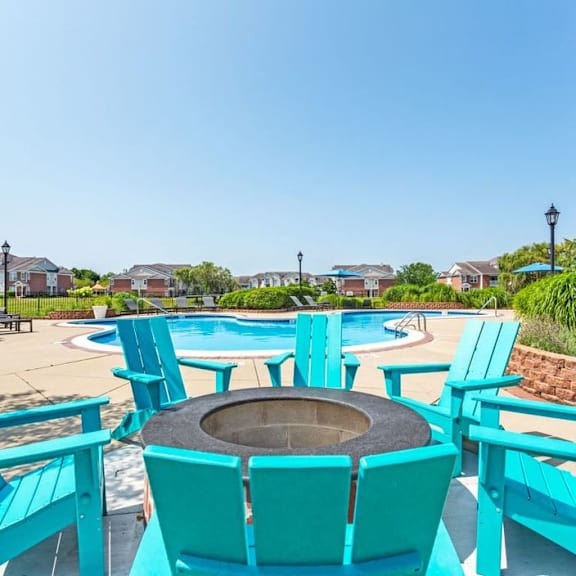 a patio with turquoise chairs and a fire pit