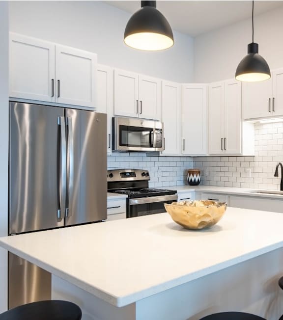 A modern kitchen with a white island and stainless steel appliances.