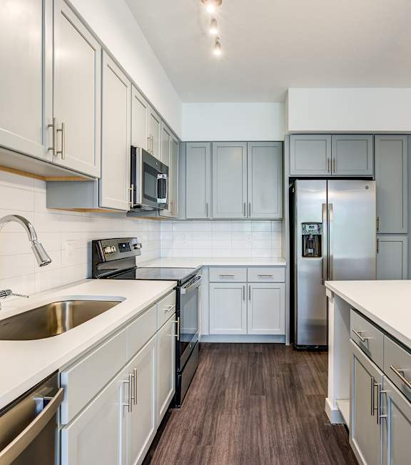 A kitchen with white cabinets and a stainless steel refrigerator.