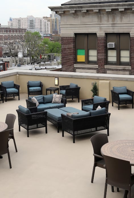 a rooftop patio with tables and chairs and a view of the city