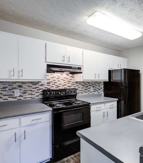 A black refrigerator stands next to a sink in a kitchen at Southland Station Apartments, Warner Robins, 31088