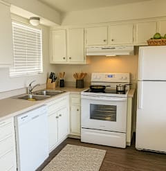A white kitchen with a stove, sink, and refrigerator.
