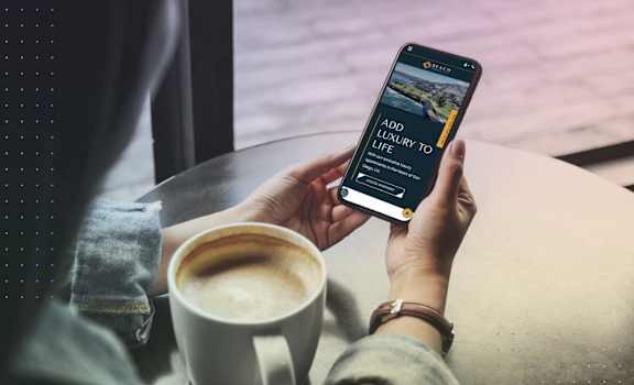 A person holding a phone with a screen displaying "ADD LUXURY TO LIFE" and a credit card.
