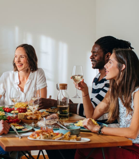 a group of people sitting around a table eating and drinking wine