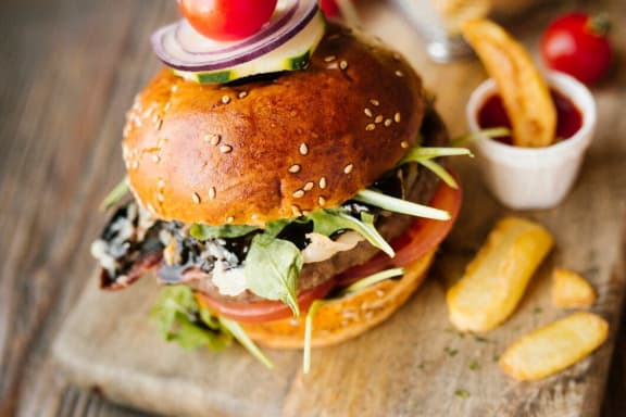 a hamburger on a wooden cutting board with fries