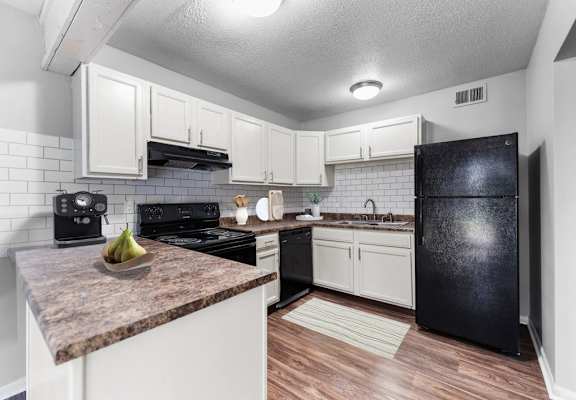 A kitchen with black appliances and white cabinets.